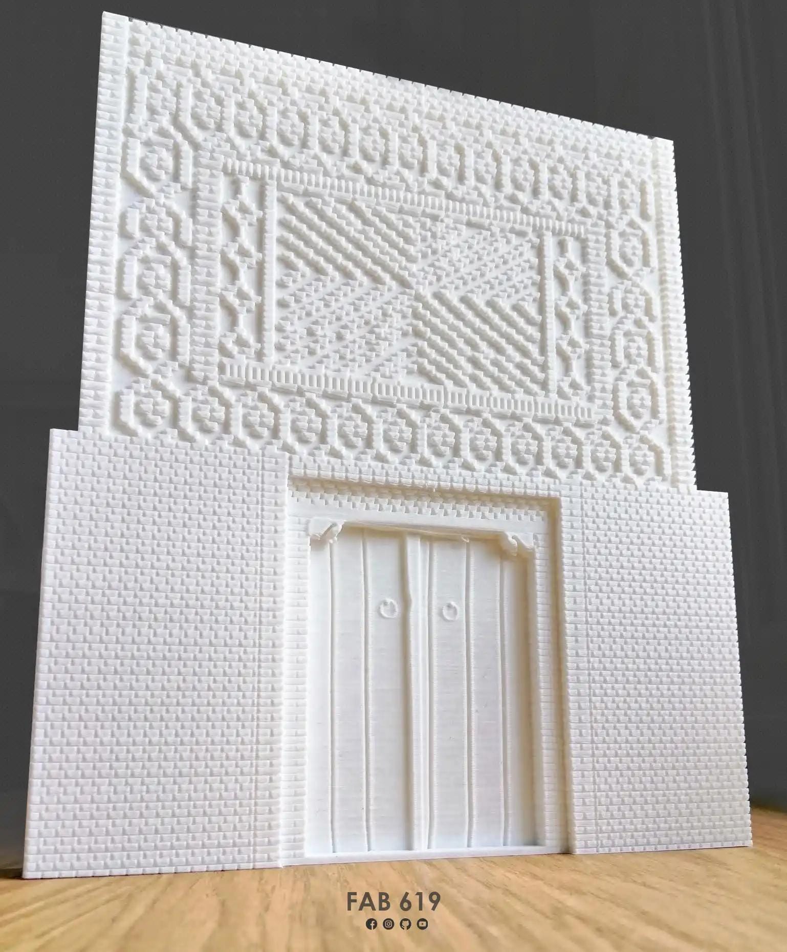 Vue en plongée de la porte traditionnelle jéridie imprimée en miniature, révélant sa structure, ses proportions et le motif géométrique en brique